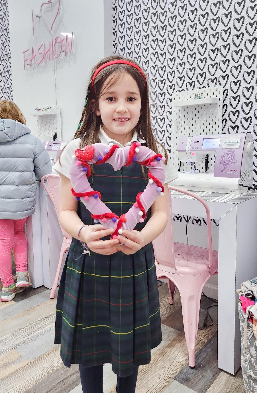 Girl holding heart sign at Valentine's craft workshop