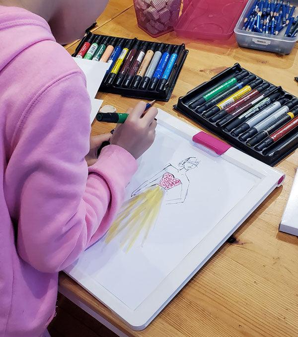 Kid drawing fashion illustration with pencil & crayons