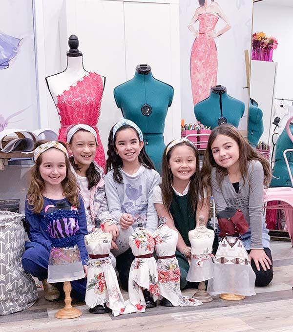 Five girls posing with their designed dresses