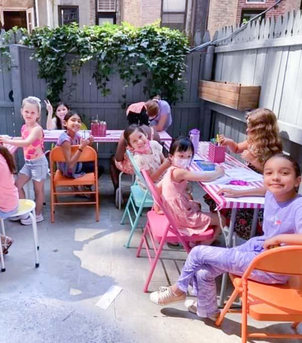Girls sitting outside learning sewing at summer camp