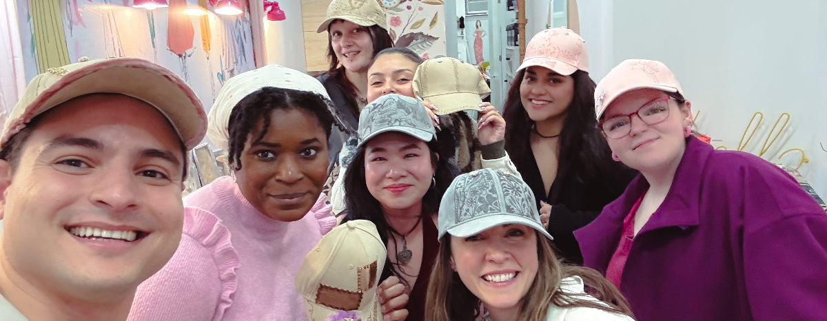 Group of people wearing hats taking a selfie in a room with floral decorations.