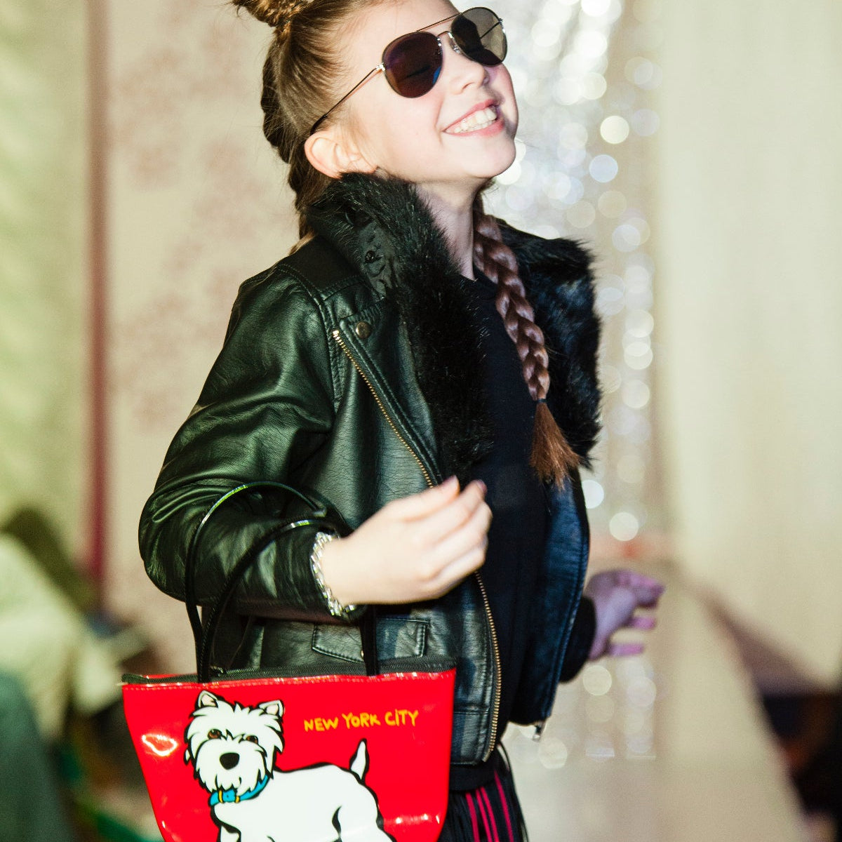 Person wearing a black leather jacket with a red bag featuring a dog illustration.
