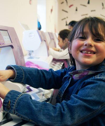 Girl smiling while working on a sewing machine