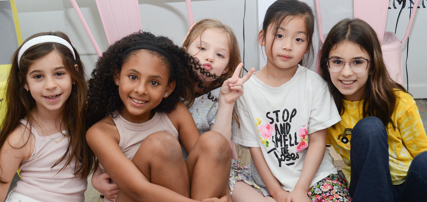Five young girls posing together in a casual setting